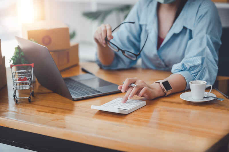 Business owner press a calculator with laptop working on a pricing strategy