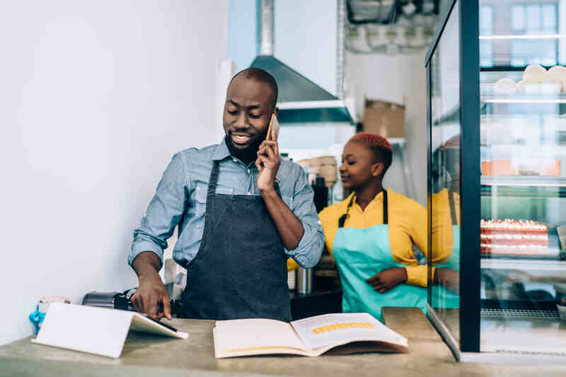 Propriétaire de magasin debout au comptoir et parlant au téléphone