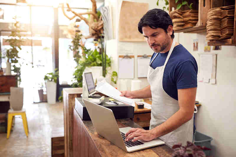 Small business owner Working On Laptop Behind Sales Desk